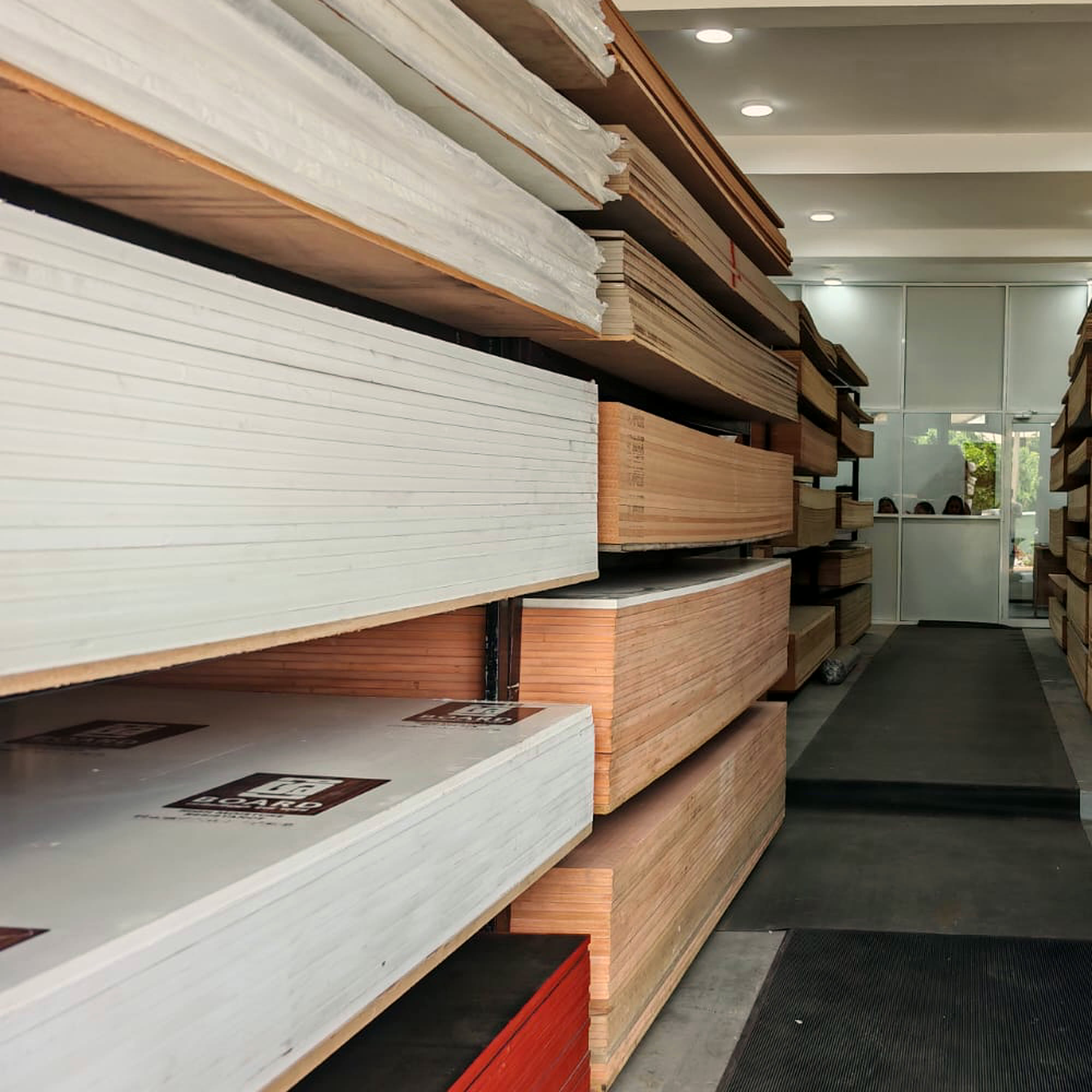 White faced melamine boards stacked on the rack, looking down the aisle toward the counter.